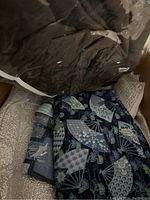 Photo showing dark fabric with fan patterns and other dark colored fabrics in a box
