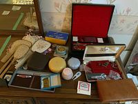 Overview of multiple items on wooden dresser including vanity set, boxes, wallet and accessories