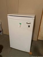 Frontal view of white Whirlpool mini fridge showing overall condition and basic shape.