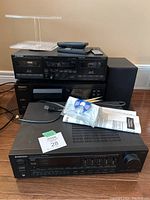 Overall view of three Pioneer stereo components stacked, speakers to side, with remotes and disc holder on top, and instructions in front.