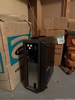 Black Argus projector model C-1 standing upright next to its original Argus box with blue and white branding.