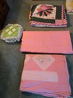 Photo showing the folded two bed quilts and crib quilt along with the lace edged cushion placed on the carpet.