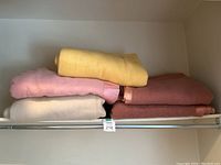 Five large wool and acrylic blankets stacked on a shelf showing colors and satin trim detail