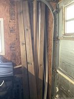 Nine 4x4 pressure treated wood posts leaning against garage wall near door