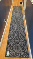 Full view of the hall runner rug placed on wooden floor, showing the repeating circular floral patterns formed by white dots on a dark background.