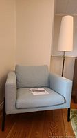 Front view of light blue Ikea Koarp armchair with metal frame, showing cushion and armrests.