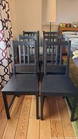 Front row of four Ikea Stefan pine dining chairs stained dark brown with vertical slat high backs and square seats