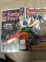 Photo of two Fantastic Four comic book covers displayed side-by-side: issue #279 with mostly dark tones and an eye icon, issue #185 featuring action artwork with Doctor Doom and X-Factor.