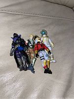 Four Fortnite action figures laid side-by-side on a light-colored couch showing details and paint