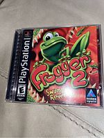 Photo showing Frogger 2 Swampy's Revenge PlayStation game in jewel case with cover art featuring cartoon frog.