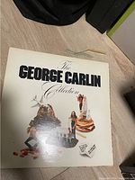 Photo of the vinyl record sleeve titled 'The George Carlin Collection' with collage artwork on front.