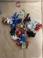 Twelve Bakugan figures displayed on a fabric surface with several ability cards.