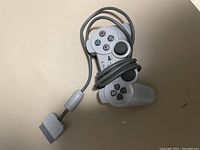 Original gray Sony PlayStation One wired controller with cable wrapped around it and original connector visible.