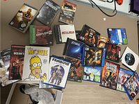 Photo showing an assortment of PS4 game cases, DVDs, PC and PS1 game cases scattered on a flat surface.