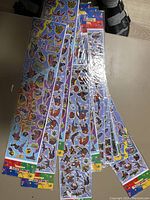 Photo showing multiple sticker sheets with Spiderman and Batman characters.