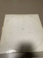 Front cover of The Beatles White Album showing white cover with embossed title and visible signs of wear.