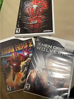Three Marvel Wii game cases: Spider-Man 3, Iron Man 2, and X-Men Origins: Wolverine, displayed on surface.