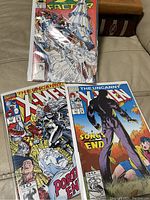 Photo of three comic books: two X-Men and one X-Factor, arranged on a beige surface, bagged in protective sleeves.