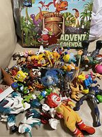 Photo showing assorted toy figurines including cartoon characters and a Dino Park advent calendar in the background.