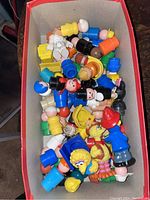 Box filled with multiple vintage Fisher Price plastic figurines including human characters and animals, some showing wear.