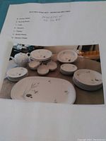 Photo of Arlington Kiln Fire Homes china set arranged on a table with paper listing included and showing pieces and quantities.