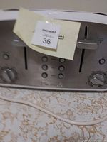 Silver stainless steel Kenmore 4-slot toaster showing front panel with control knobs, buttons, and lift levers on a kitchen countertop.