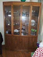 Full frontal photo of the Kroehler solid wood china cabinet showing glass front doors with glassware inside and closed wooden lower doors.