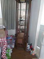 Full view of tall wooden vintage glass display cabinet with glass front door, three glass shelves, and bottom wood storage cabinet. Interior light visible.