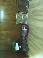 Photo showing three small wire cages and one soft pet bed for small pets on a wooden floor in front of a wooden wall.