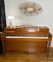 Front view of the Howard upright piano showing wooden finish, keyboard with 88 keys, three pedals, and some minor scratches on the cabinet.