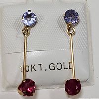 Front-facing close-up of both earrings showing tanzanite and ruby stones, 10K gold markings in the background.