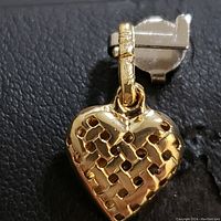 Close-up front and side views of a 14 karat yellow gold heart-shaped pendant featuring a lattice cut-out pattern and polished finish.