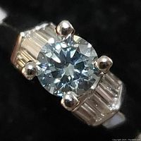 Front view of ring showing round center diamond and tapered baguette side stones from top