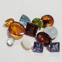 Close-up of 12 assorted genuine loose gemstones, various shapes, colors and cuts, totaling about 5 carats.