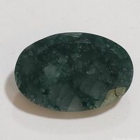 Clear top-down image of oval green emerald with visible inclusions.