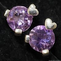 Close-up front view of one earring highlighting the round amethyst and silver heart detail.