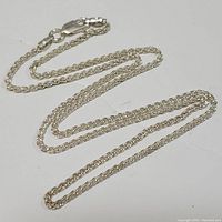 Full view of the sterling silver chain necklace coiled on a white surface showing the overall condition and design.