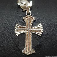 Front view of sterling silver cross pendant showing raised and textured linear design with polished finish.