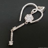 Front view of sterling silver heart-shaped pendant with cubic zirconia stones, showing flower cluster and dangling drop.