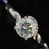 Close-up photo of the sterling silver ring with a round faceted moissanite stone at center set in prongs with a twisted band design