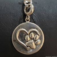 Sterling silver necklace pendant close-up showing heart and paw print design