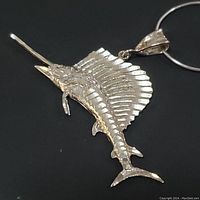 Close-up front view of sterling silver sailfish pendant on silver chain, showing detailed fins and head features.
