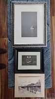 Three framed artworks arranged vertically on a carpet, showing the full set included in the lot.