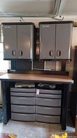 Full view of storage system showing two wall cabinets above, workbench surface, and plastic drawer unit below