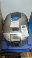 Front view of Zojirushi rice cooker with label showing it is for sale and description as rice cooker.