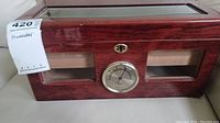 Front view of rectangular wooden humidor with glass top, hygrometer below glass panel, and wood finish.