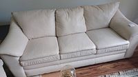 Front view of off-white leather three-seat sofa on wood floor