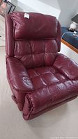 Front view of burgundy recliner chair, showing overall condition and padded seat, backrest, and armrests.