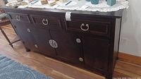 Front view of dark wood buffet server cabinet with metal ring handles and four cabinet doors.