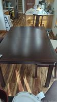 View of full dining table with leaf installed, showing dark wood finish and rectangular shape.